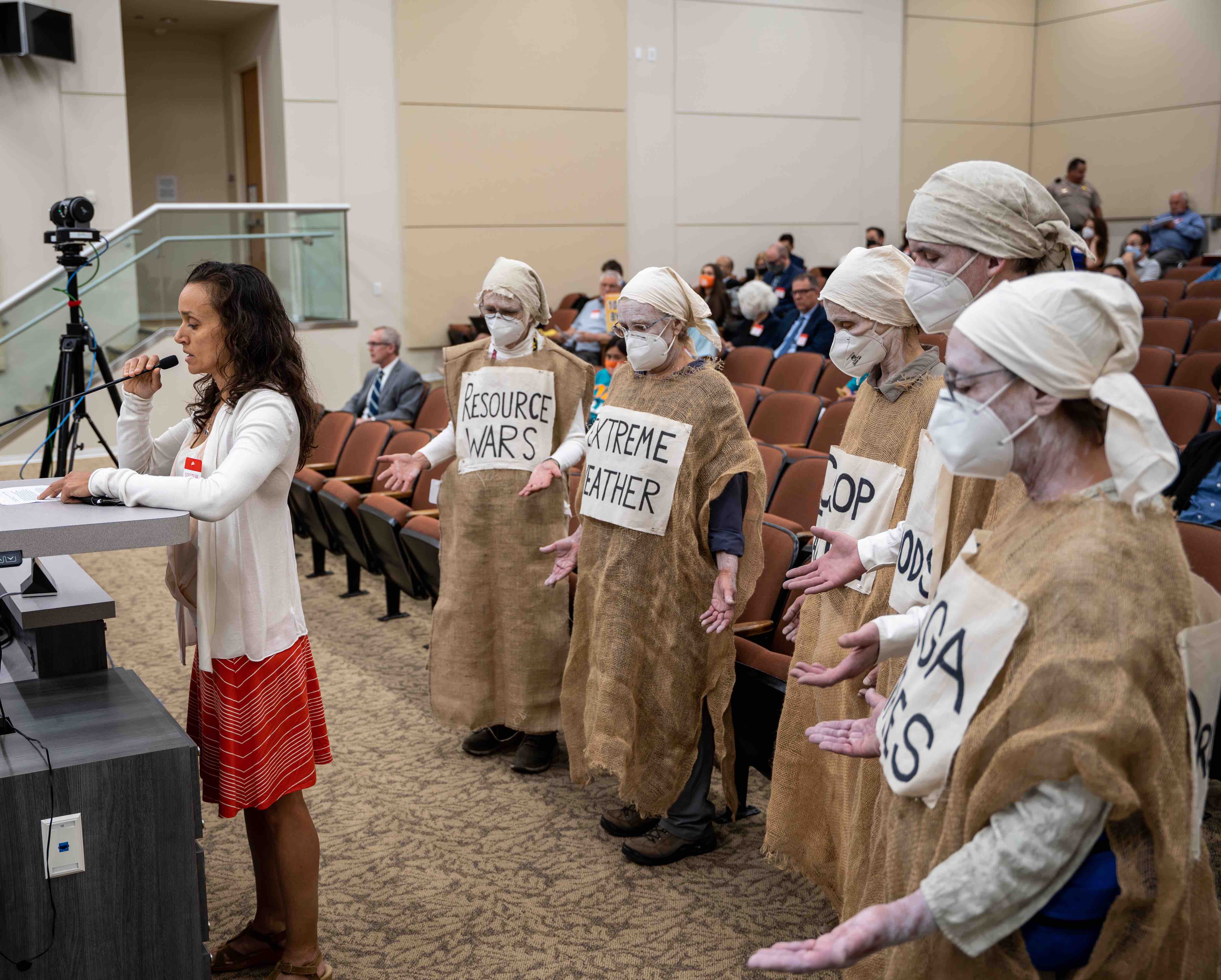 Lamentors stand behind speaker at a board meeting